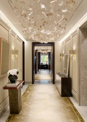 Elegant Hallway that features a console table with a red top and bronze base, and a sideboard with sycamore black casing and sycamore pearl doors - A Serene and Artisanal Luxury Home in Mayfair